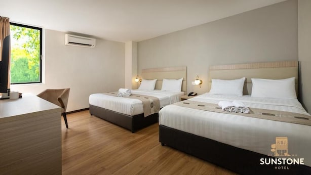 Camera d'albergo con due letti, una scrivania, una sedia e un condizionatore.