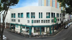 Un edificio a più piani con facciata piatta, diverse finestre e un tendone verde.