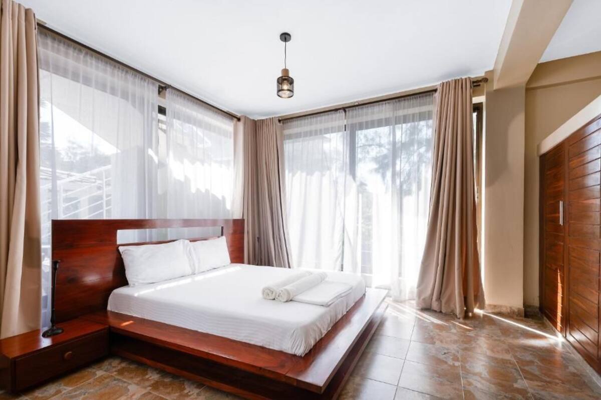 A spacious bedroom with a large bed, wooden headboard, and a view of the outdoors.