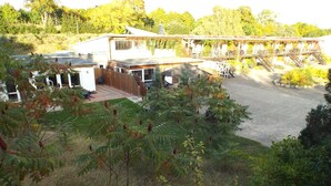 Ein Wohnhaus mit überdachter Terrasse, umzäunter Garten und einer Holztreppe zu einer zweiten Etage.