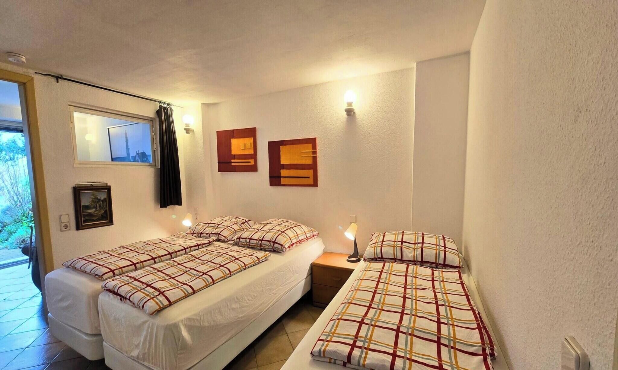 Une petite chambre agréable, dotée de deux lits, d’une fenêtre offrant une belle vue et d’un luminaire fixé au mur.