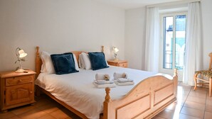 Ein ordentlich bezogenes Bett mit Kissen, einem Holzkopfstück und zwei Nachttischen mit Lampen.