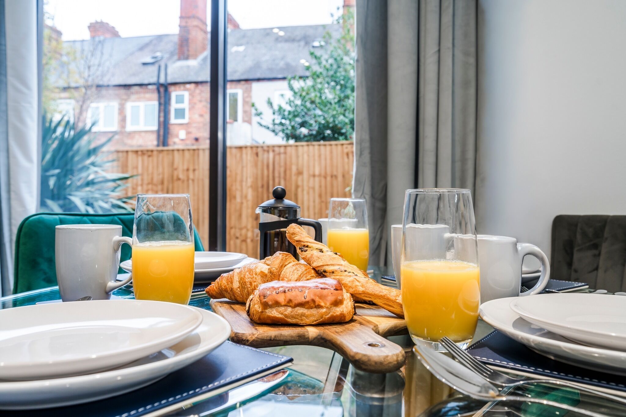 A breakfast setup with croissants, orange juice, and a coffee maker on a table.