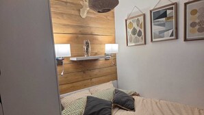 A bedroom with a bed, pillows, a hanging light fixture, and wall art. - La parenthese suspendu (Font-Romeu-Odeillo-Via)