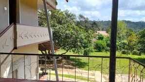 Ein Gebäude mit Balkon, Treppe und Blick auf eine grüne Landschaft.