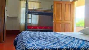 Ein Zimmer mit Etagenbett, Holzschrank und einem fenster mit Vorhängen.