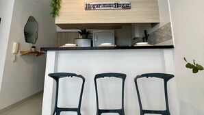 Una cocina con encimera de madera, tres taburetes negros y un letrero sobre la encimera.