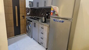 Eine kleine Küche mit Waschmaschine, Kühlschrank und Holzausstattung.