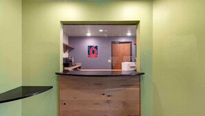 Un mostrador de recepción con un logotipo, una barra y una puerta al fondo.