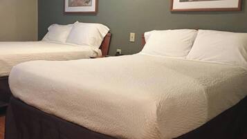 Two twin beds with white bedding, a wooden headboard, and a framed picture on the wall.