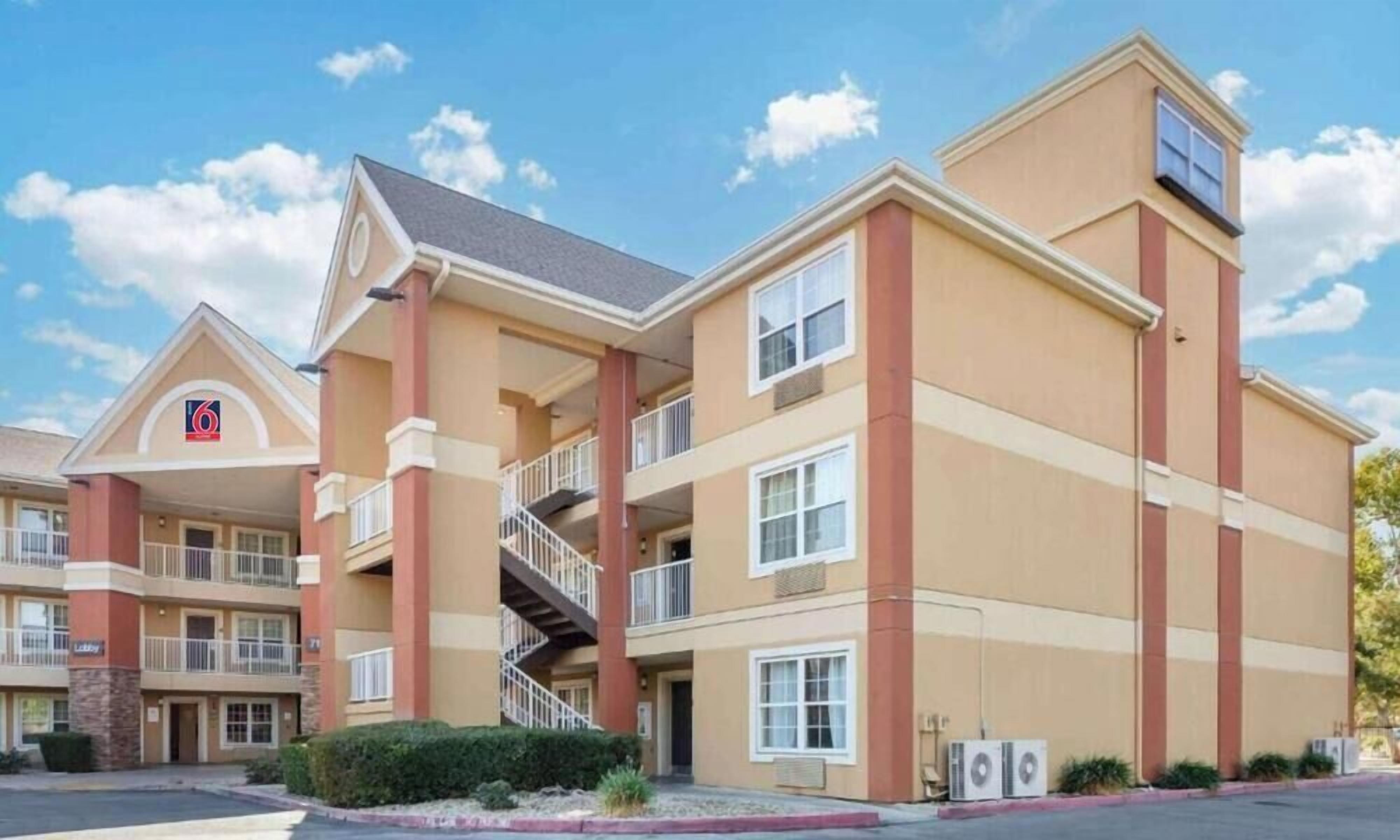 A multi-story hotel with a prominent '6' logo, balconies, and a central staircase.
