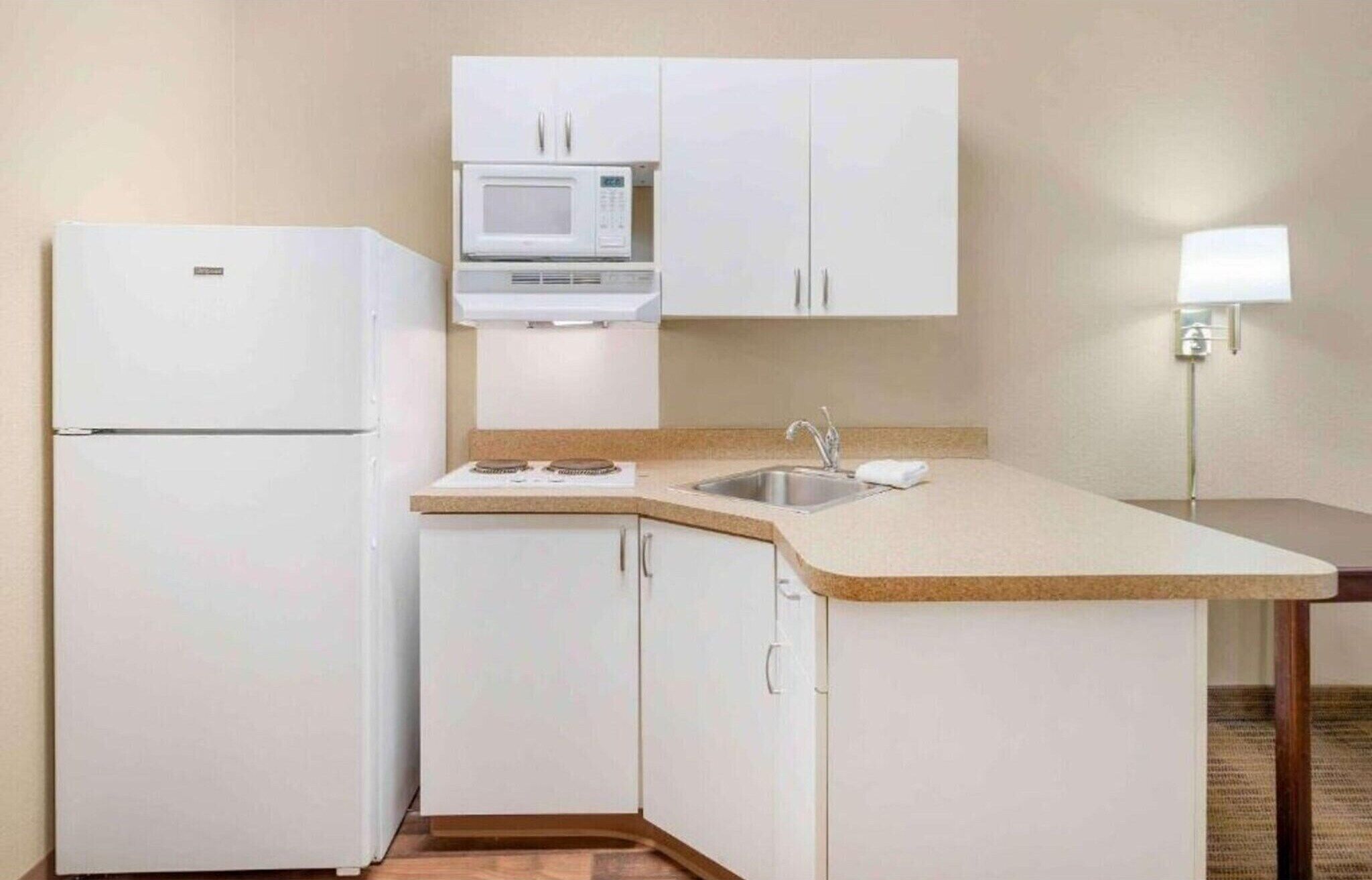 Une cuisine compacte équipée d’un réfrigérateur, d’un four à micro-ondes, d’un évier et d’un petit plan de travail.