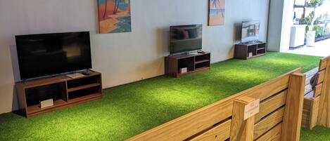 Una habitación con una televisión de pantalla plana, un banco de madera y una pared con obras de arte.