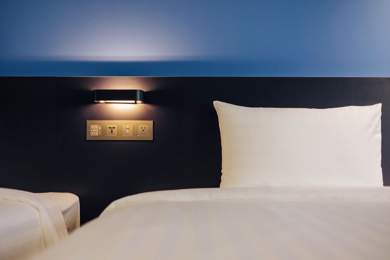 Une chambre d’hôtel avec un lit, un panneau de commande fixé au mur et une vue sur l’océan.
