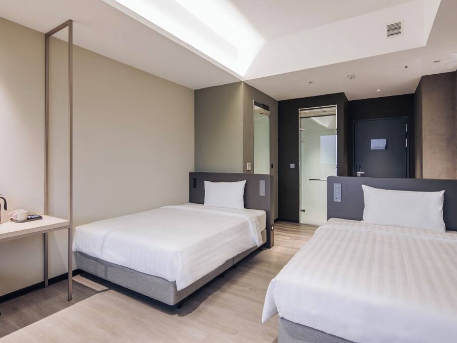 Een hotelkamer met twee bedden, een bureau, een koffiezetapparaat en een spiegel.