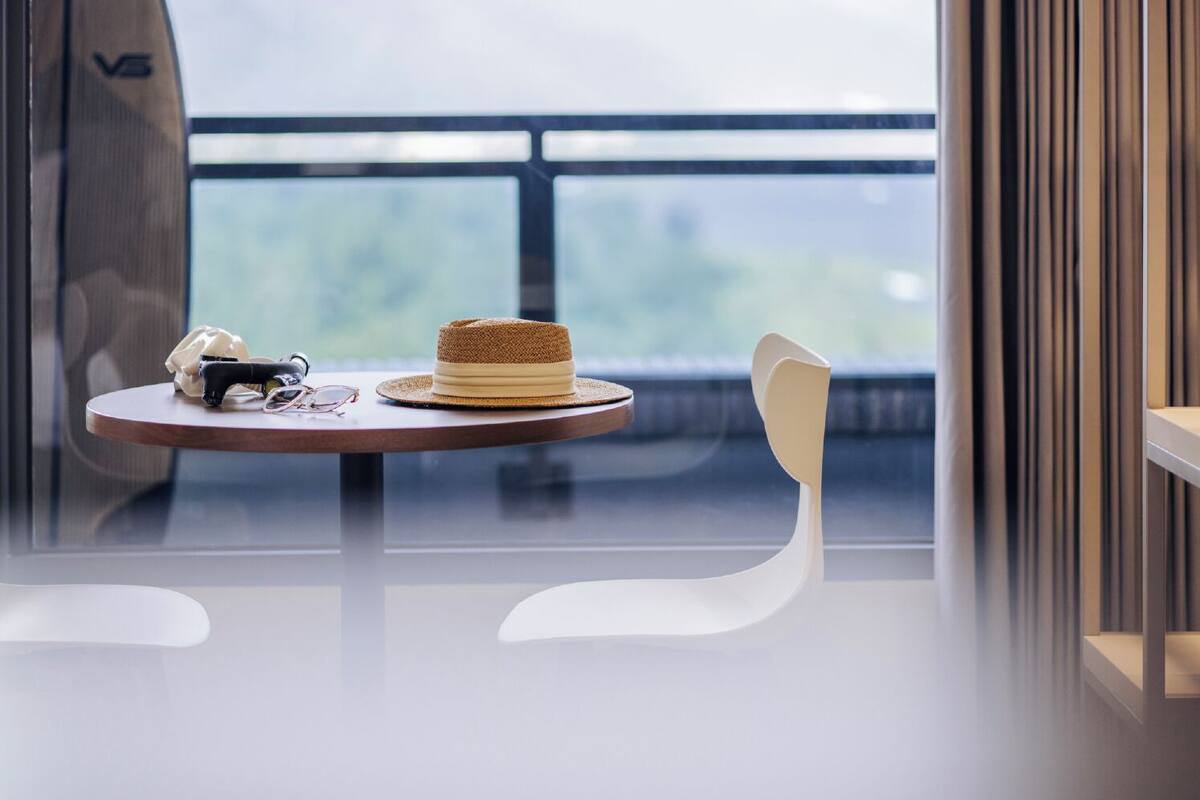 A modern room with a glass table, a hat, a telephone, and a chair.