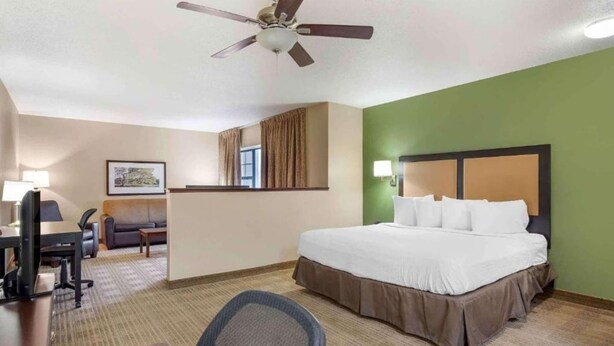 Une chambre d’hôtel équipée d’un lit, d’un bureau, d’une chaise et d’un ventilateur de plafond.