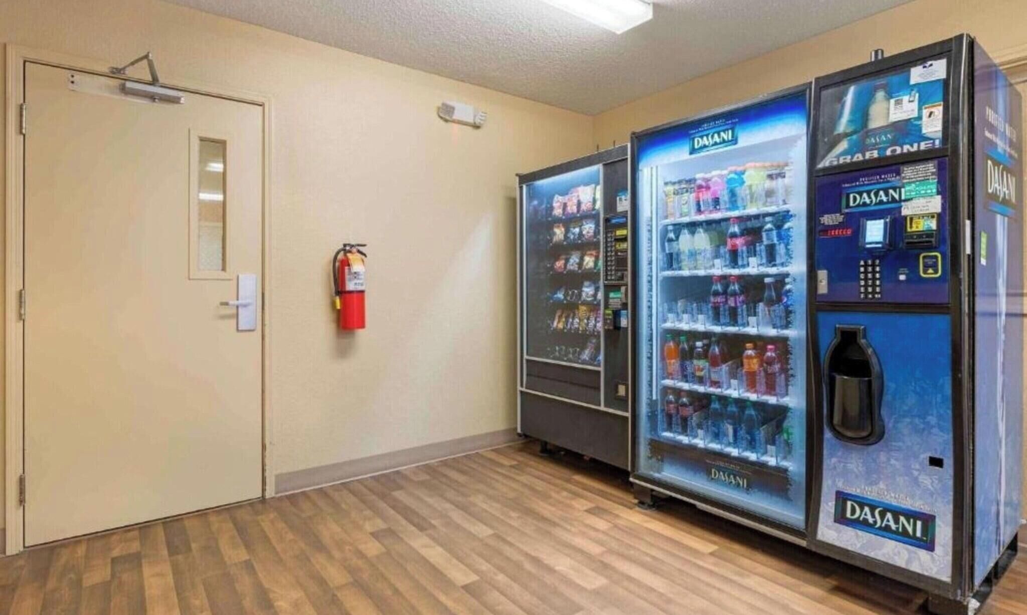 A hallway with two Dasani water coolers and a fire extinguisher on the wall.