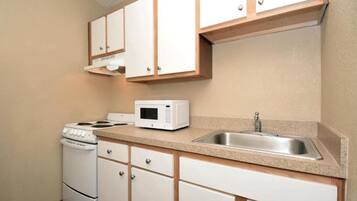 A kitchen with white cabinets, a microwave, a stove, and a sink.