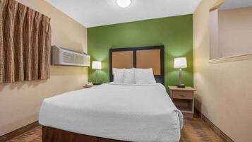 Une chambre d’hôtel équipée d’un lit, de deux lampes de chevet, d’un climatiseur et d’un rideau fixé au mur.