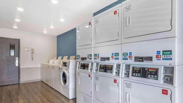 A laundry facility with multiple machines, each marked with a number and payment options.