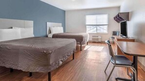 A hotel room with two beds, a desk, a chair, a television, and a window with blinds.