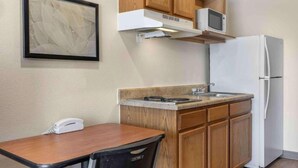 Una cocina compacta equipada con microondas, refrigerador y una pequeña mesa de comedor con sillas.
