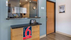 A reception desk with a sign indicating '6 suites,' a clock, and a framed picture on the wall.