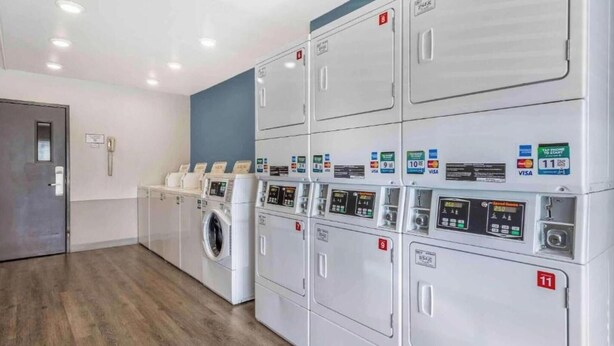 A laundry facility with multiple machines, each marked with a number and accepting various payment methods.
