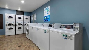 A laundry facility with multiple washing machines and dryers, a wall-mounted sign, and a tiled floor. - 1 Full Bed | ADA/Tub/Non-Smoking/Kitchen (Shreveport LA)