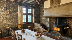 Een eetruimte met een stenen muur, houten balken, een open haard en een ontbijttafel.