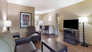 Een hotelkamer met een bank, een televisie, een bureau en een stoel.