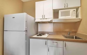 A compact kitchen with a white refrigerator, a microwave, a stove, and a sink. - 1 Queen Bed | ADA/RI Shower/Non-Smoking/Kitchen (Germantown)