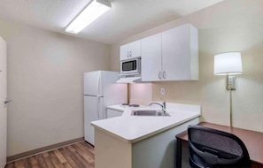 A compact kitchen with a refrigerator, microwave, and a small island with a sink.