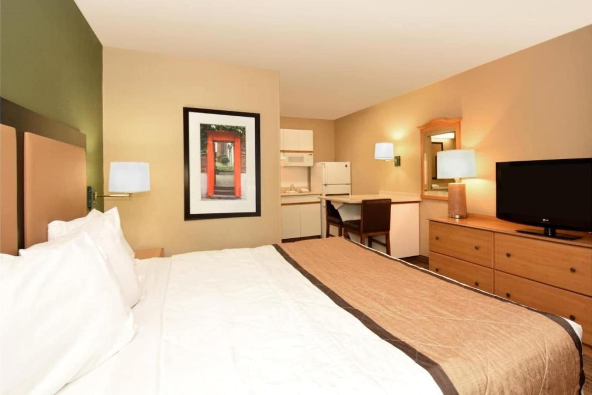 Une chambre d’hôtel équipée d’un lit, d’un bureau, d’une télévision et d’une kitchenette.