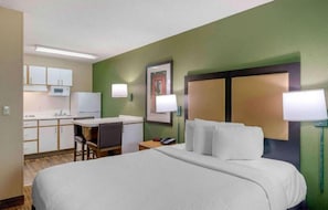 Ein Hotelzimmer mit Bett, Schreibtisch, Stuhl, Mikrowelle und Kühlschrank.