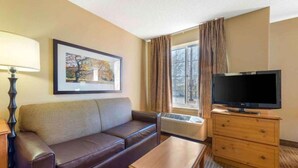 A hotel room with a sofa, a TV, a small table, a lamp, and a picture on the wall. - 1 King Bed | Non-Smoking, Kitchen (Minneapolis MN)