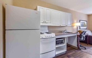 Una cocina compacta con refrigerador, estufa, horno y pileta.