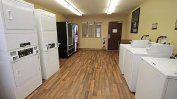A laundry room with stacked washers and dryers, a refrigerator, and a sink area.