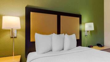 Habitación de hotel con cama, dos lámparas de noche, una mesita de noche y teléfono instalado en la pared.