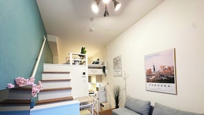 Ein modernes Wohnzimmer mit einer Couch, einem kleinen runden Tisch, einer Treppe und einem Stadtblick-Poster an der Wand.