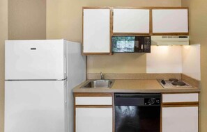 Cozinha compacta com geladeira, micro-ondas, fogão, pia e lava-louças.