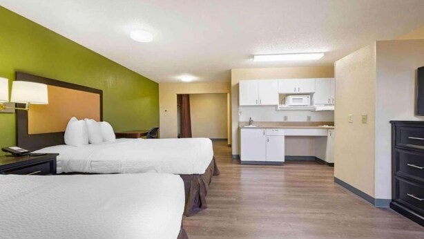 Une chambre d’hôtel avec deux lits, une kitchenette et une salle de bain.