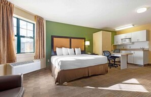 Ein Hotelzimmer mit Bett, Schreibtisch, Stuhl und einer Küchenzeile.