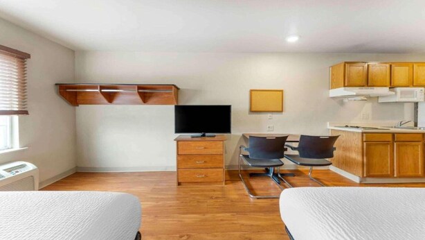 A compact hotel room with a kitchenette, a flat-screen TV, a desk with two chairs, and two beds. - 2 Full Beds | Smoking, Kitchen (Oklahoma City OK)