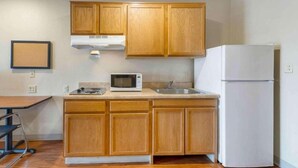 A kitchen with wooden cabinets, a microwave, a stove, and a refrigerator. - 2 Full Beds | Smoking, Kitchen (Oklahoma City OK)