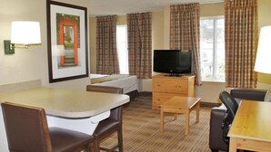 Ein Hotelzimmer mit Bett, Fernseher, Esstisch und Sofa.