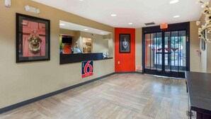 A hotel reception area with a reception desk, a framed artwork on the wall, and a door with an exit sign. - 2 Full Beds | Non-Smoking, Kitchen (Seattle)