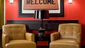 A hotel lobby with a red wall, a welcome mat, two leather armchairs, and a side table with a lamp. - 2 Full Beds | Non-Smoking, Kitchen (Seattle)