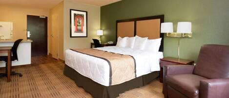 Une chambre d’hôtel équipée d’un lit, d’un bureau, d’une chaise et de deux lampes de chevet.